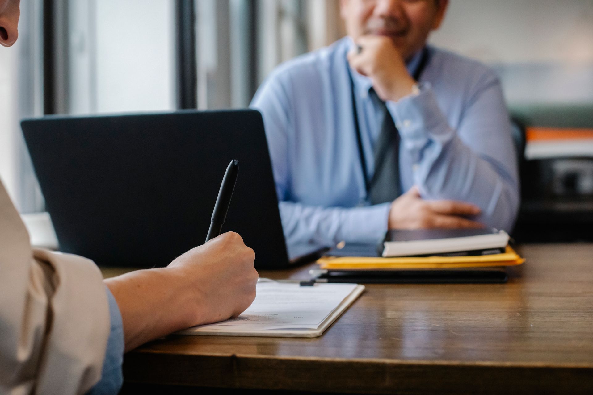 Candidate completing application paperwork beside a laptop